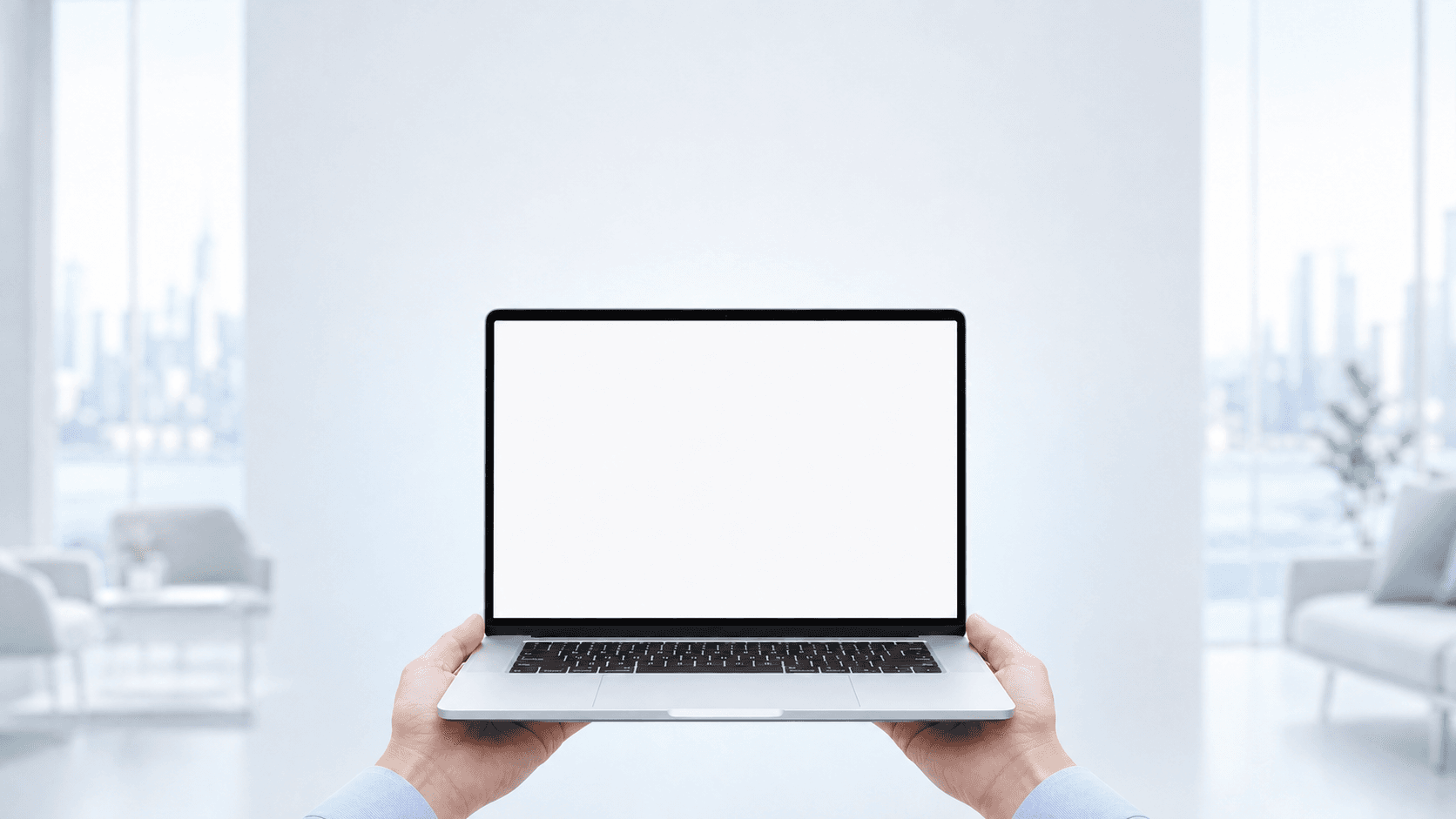A silver laptop held in a bright modern office